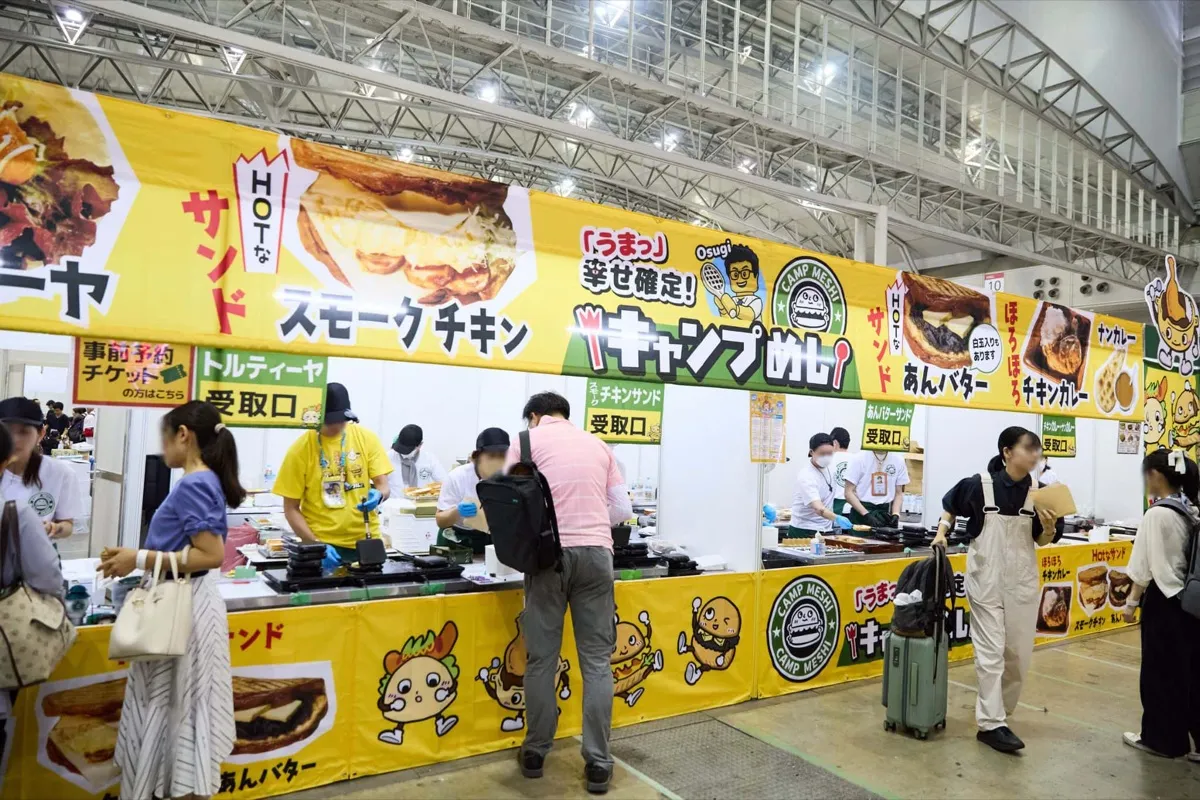 メニュー看板を掲げたキッチンブースに並ぶ来場者